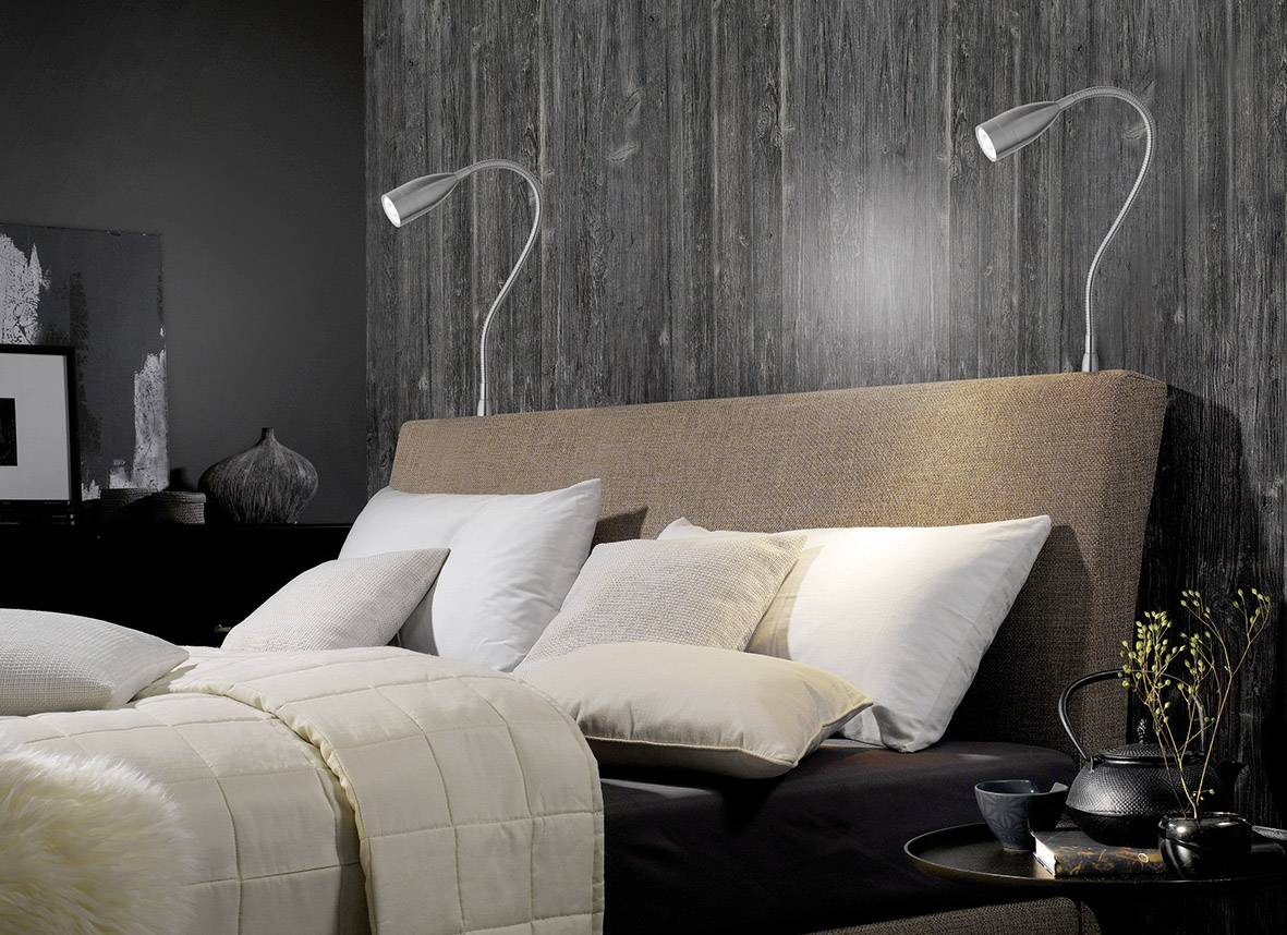 Ugodan spavaći sobar s velikim krevetom ukrašenim jastucima i pokrivačima. Dvije lampe za čitanje pričvršćene su na zidu.