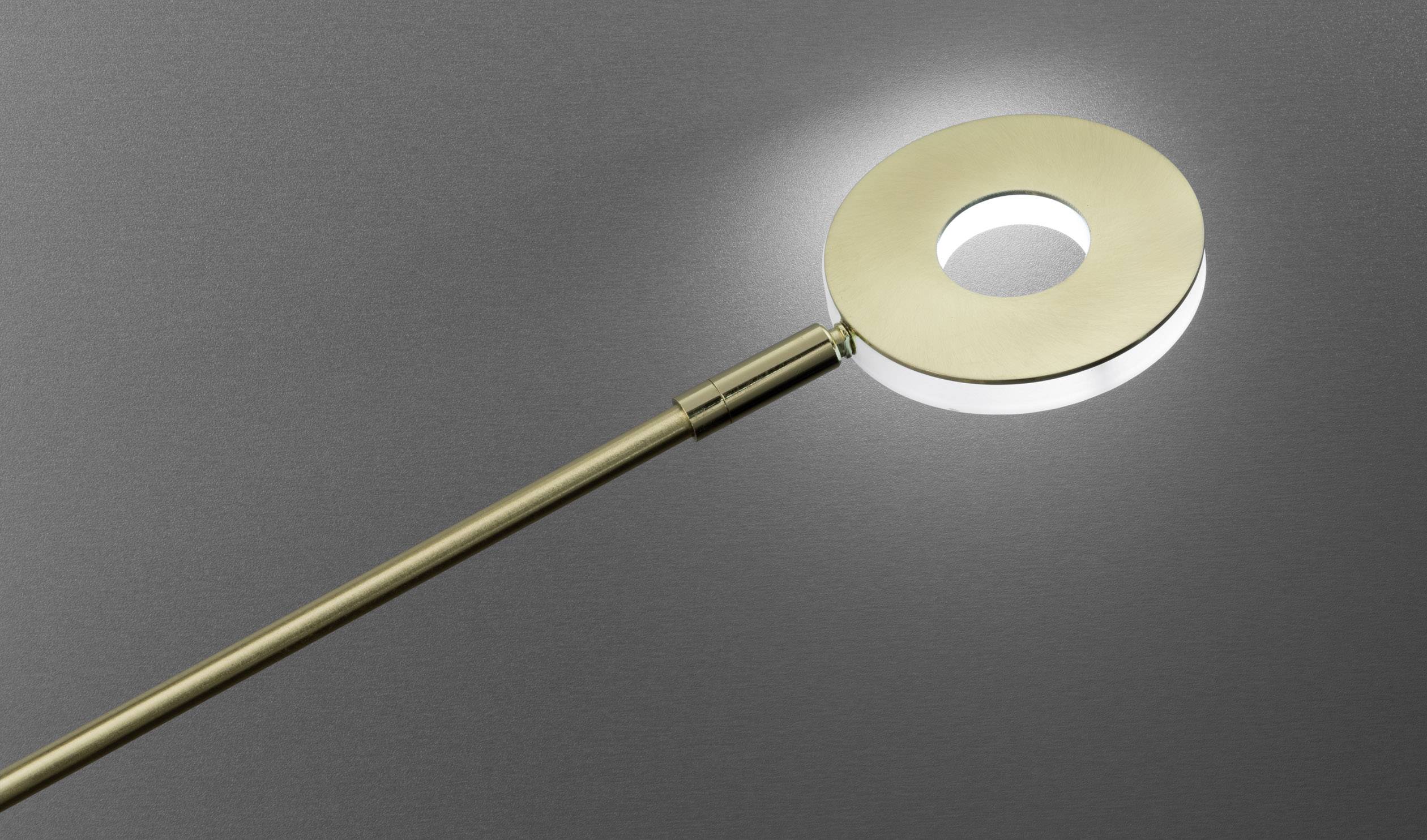 Moderna, okrugla lampa s rupom u sredini, pričvršćena na tankoj metalnoj ruci, blago osvjetljava sivi pozadinski prostor.