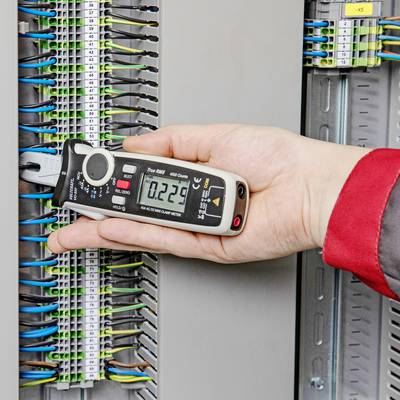Jedna osoba drži digitalni mjerni uređaj na otvorenom električne razvodnoj kutiji kako bi izmjerila električne signale. Kabeli su vidljivo priključeni.