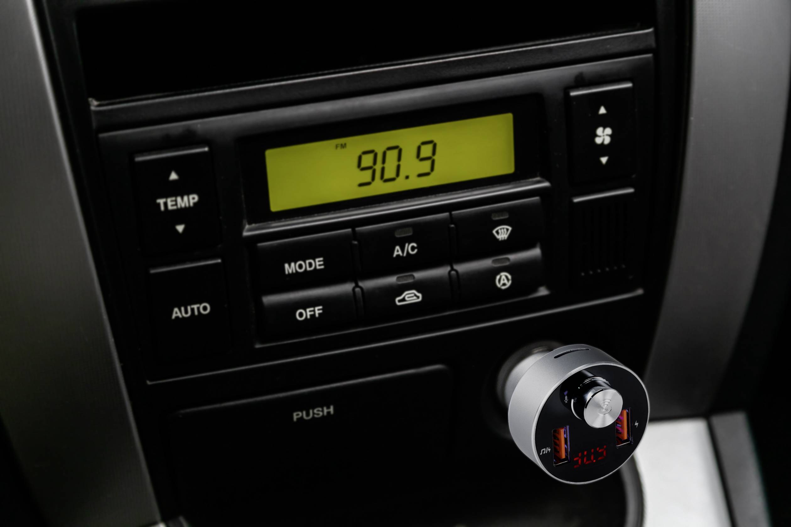 Auto-radio zaslon prikazuje frekvenciju 90,9. Upravljačka ploča klimatizacije ispod njega sadrži regulator temperature, odabir načina rada i simbole ventilacije.