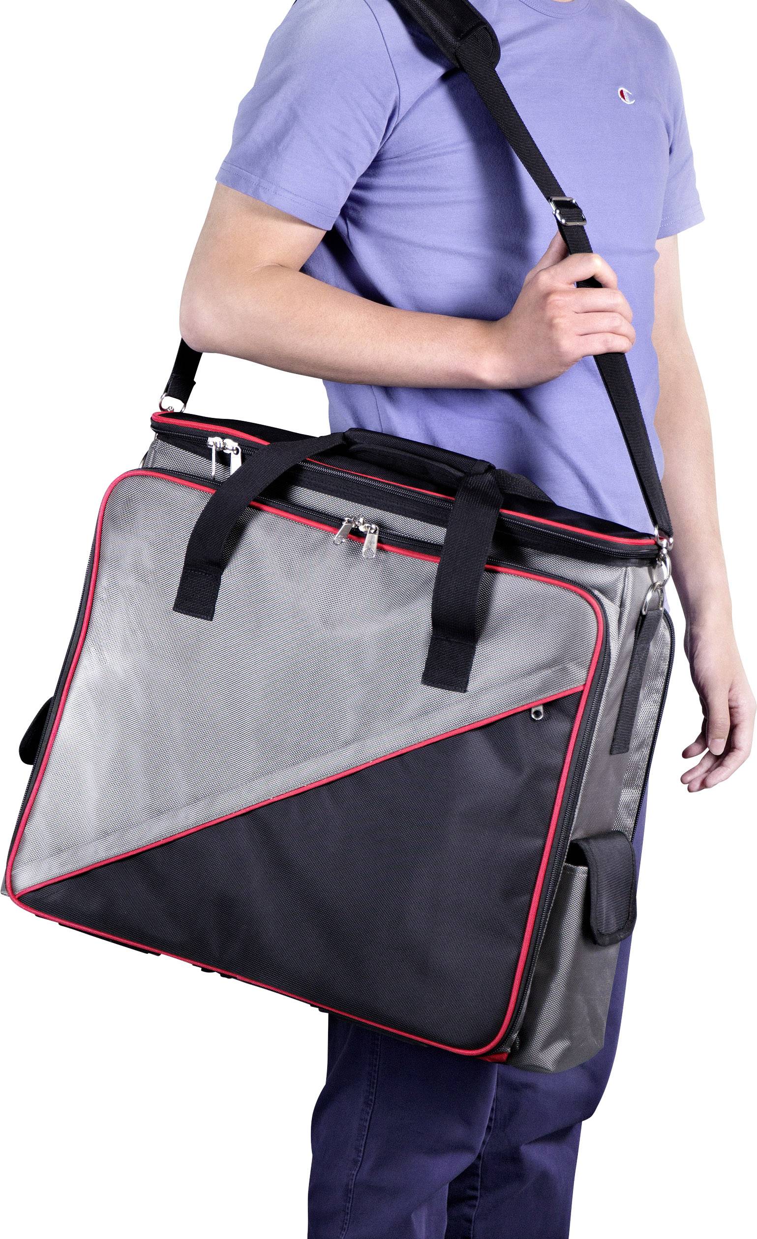 Osoba u plavim hlačama i majici nosi veliku, sivu torbu s crvenim naglascima preko ramena.