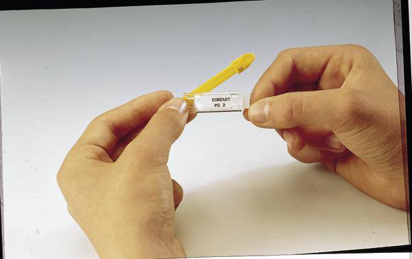 Dvije ruke drže malu, prozirnu epruveticu sa žutim čepom, označenu natpisom 'Circuit PO 2'.