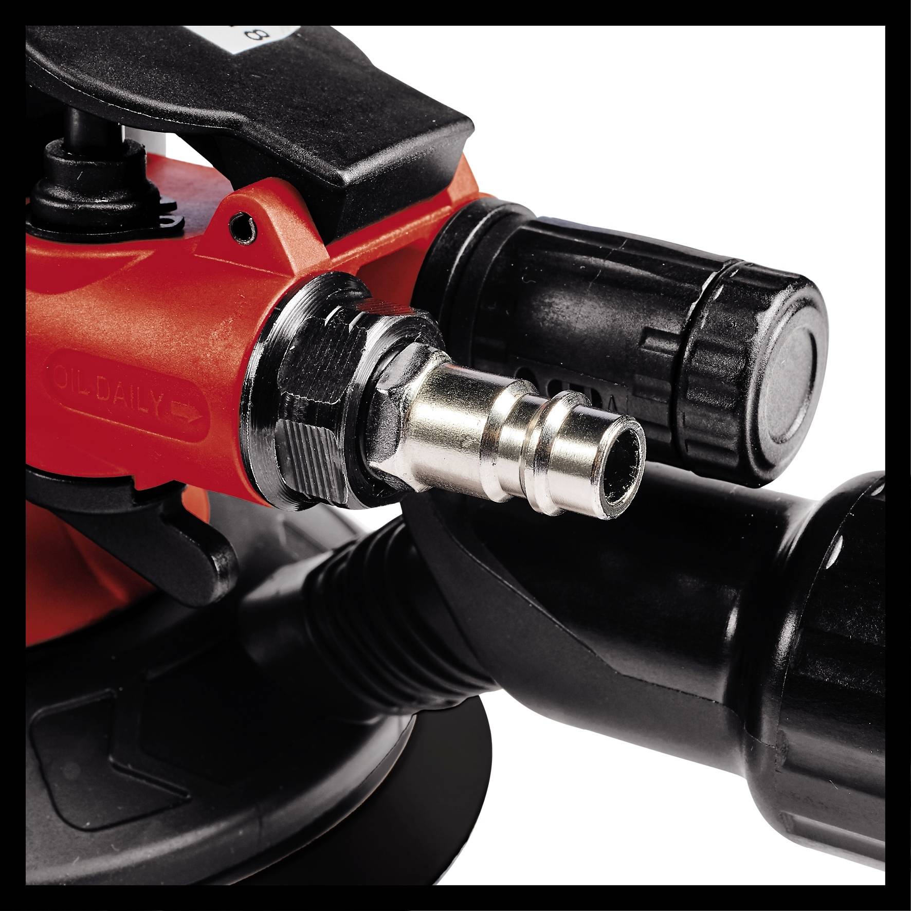 Bliski kadar crvene spojnice za komprimirani zrak povezane s crnom cijevi, okružene upravljačkim elementima.