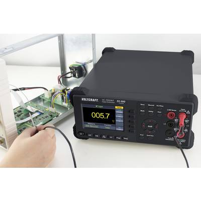 Mjerni uređaj tvrtke VOLTCRAFT, model VC7055BT, prikazuje vrijednost od 0,05 V. Povezan je s tisknom pločicom. Jedna ruka drži mjerni kabel.