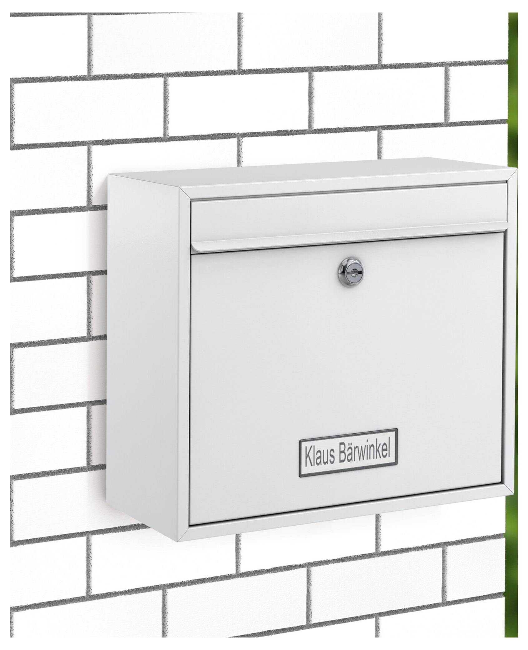 'Bijeli poštanski sandučić označen imenom Klaus Bärwinkel montiran na bijelom zidu od cigla.'