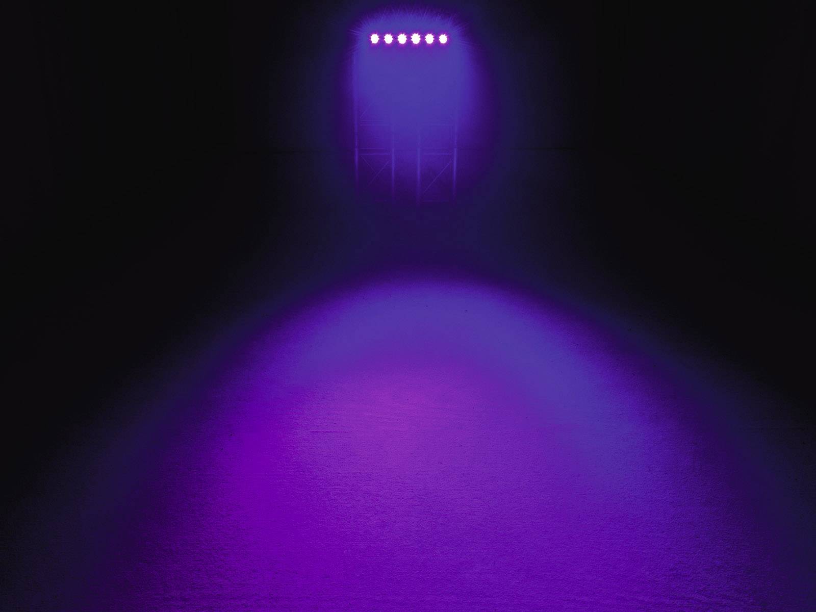 Lila Lichtstrahl osvjetljava pozornicu odozgo, tamna pozadina, bez vidljivih objekata ili osoba.