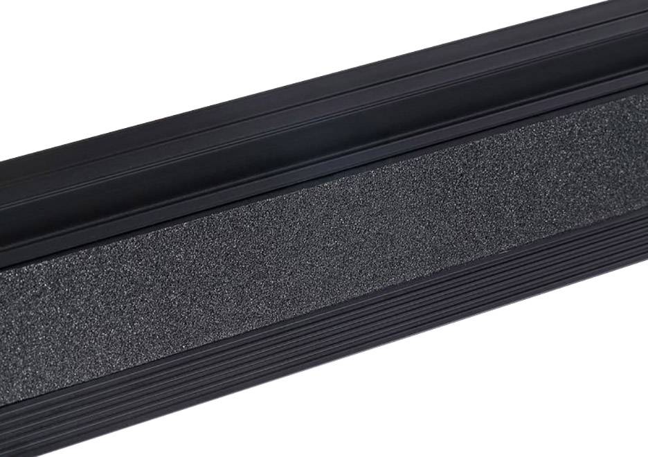 Bliski kadar protukliznog gumenog traka na tamnoj podlozi, korišten za sigurnost na stepenicama ili rampama.