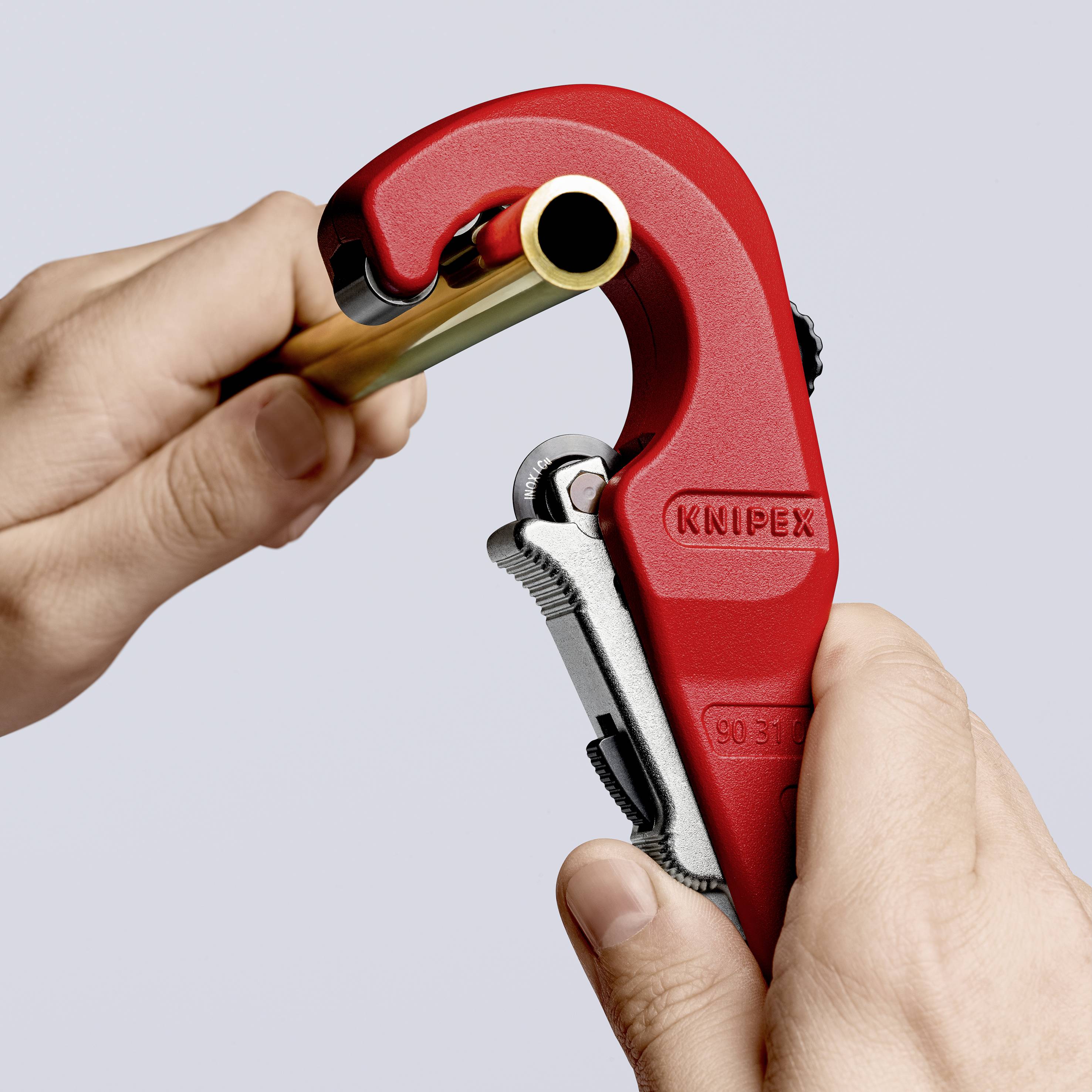 Ruka drži KNIPEX rezač cijevi dok se cijev reže. Približni kadar alata u upotrebi.
