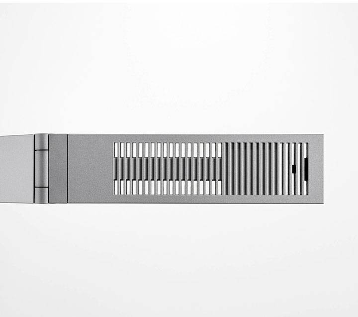 Siva, pravokutna naprava s prorezima koja predstavlja moderan sustav grijanja ili ventilacije, na bijeloj pozadini.