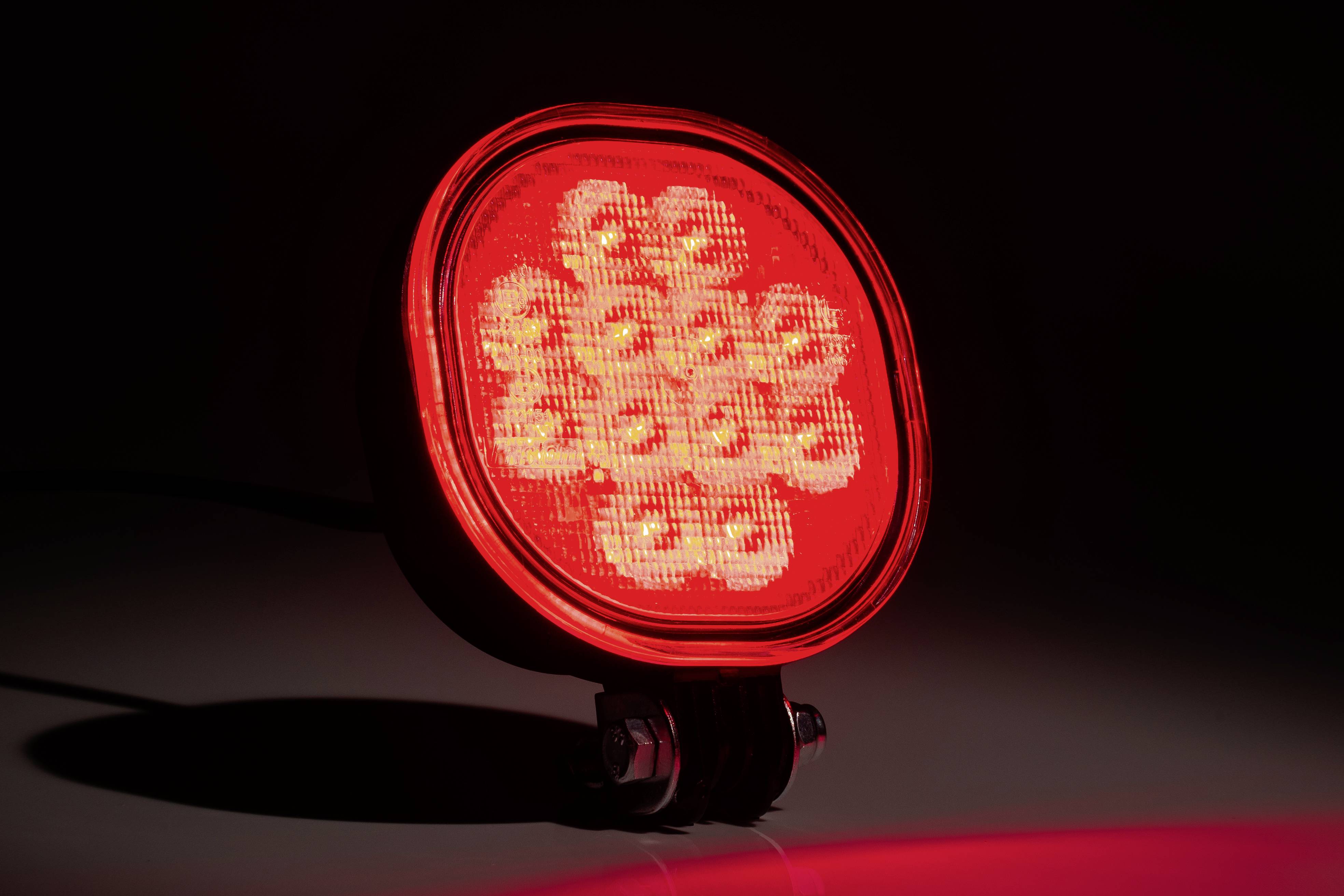 Okrugla crvena LED-lampica svijetli jako na tamnoj pozadini, simbolizirajući upozorenje ili signalizaciju.