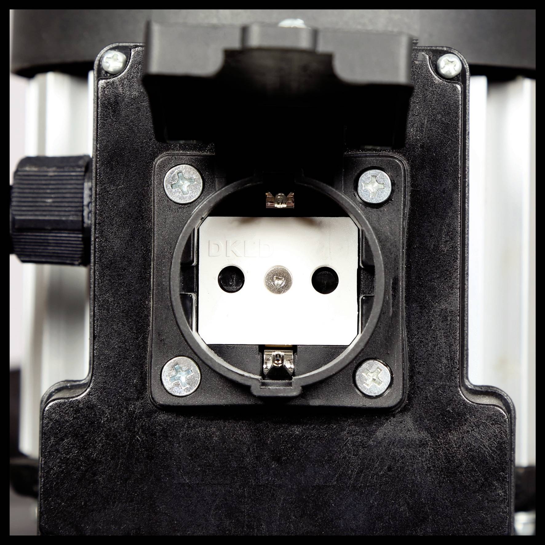 Bliski kadar crne nosač uređaja s vidljivim vijcima i okruglim priključkom u sredini.