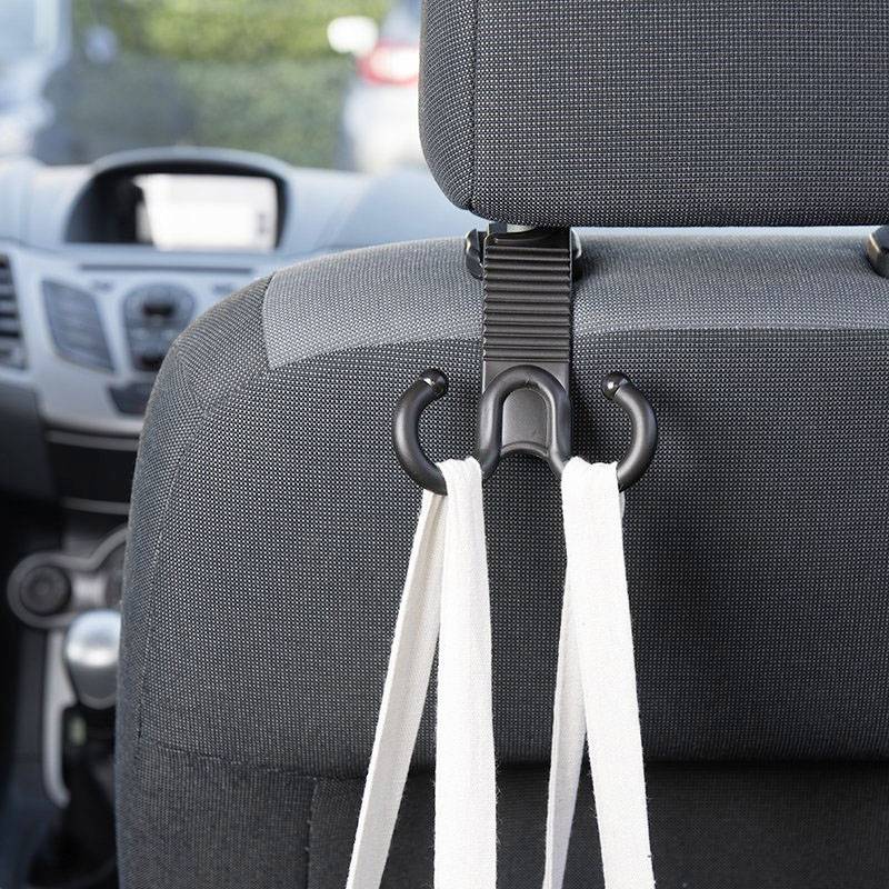 Sivi organizator za naslon sjedala automobila s kukicama drži dvije bijele torbe. U pozadini se vidi instrument-ploča.