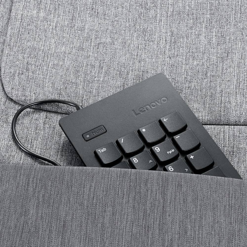 Lenovo tipkovnica s kabelom djelomično je utaknuta u sivo jastučić kauča. Brojčane tipke su vidljive.