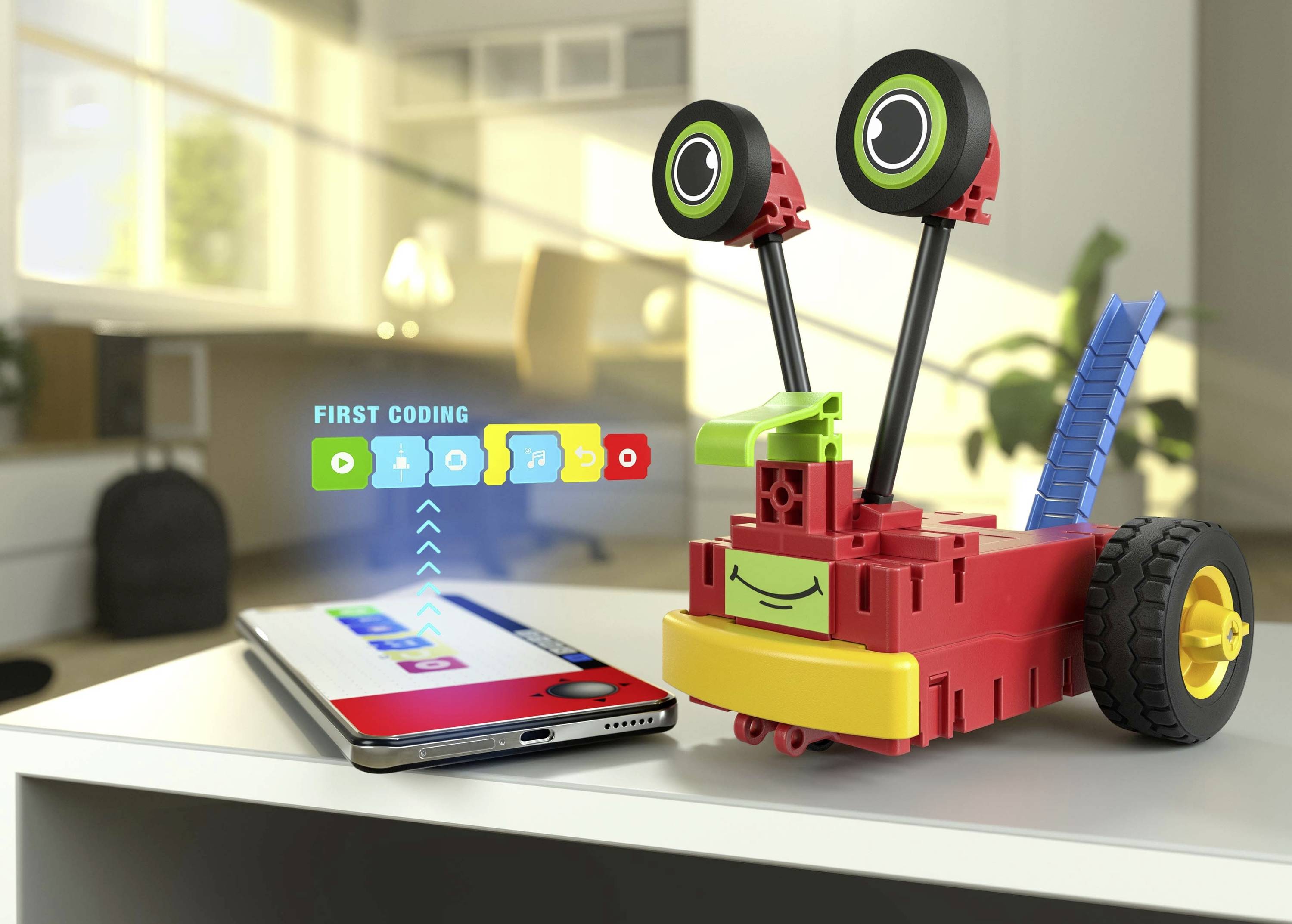 Šarena robotska igračka s kotačima, povezana pametnim telefonom, prikazuje aplikaciju za kodiranje namijenjenu upravljanju i programiranju.