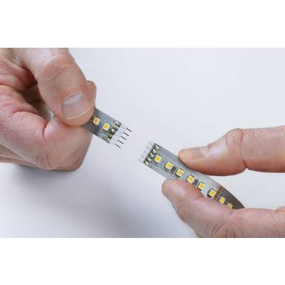 Dvije ruke spajaju LED traku putem konektora. Bijela pozadina naglašava elektroničke komponente.