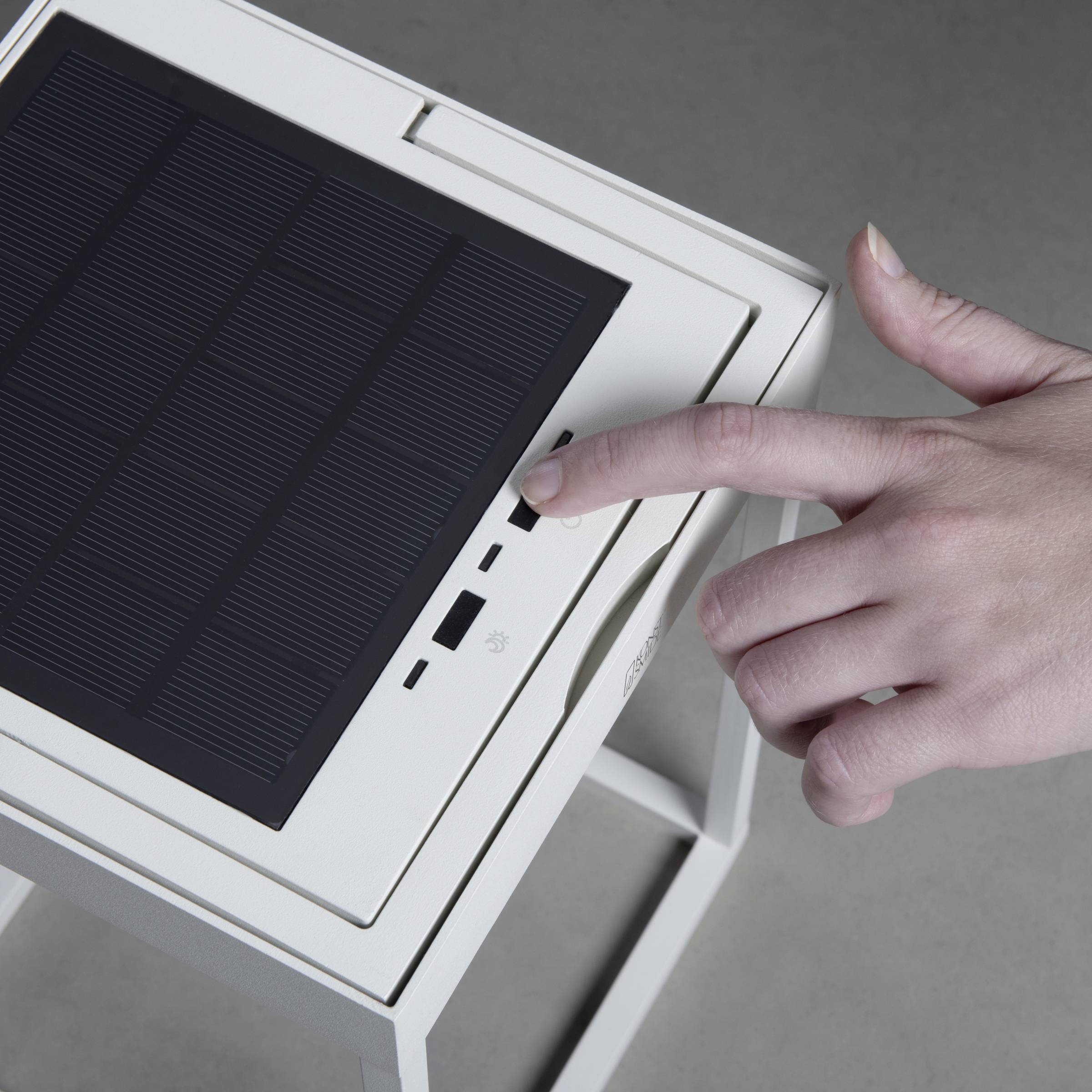 Jedna osoba rukuje uređajem koji ima solarni panel i USB priključak. Pritišće tipku pored priključka.
