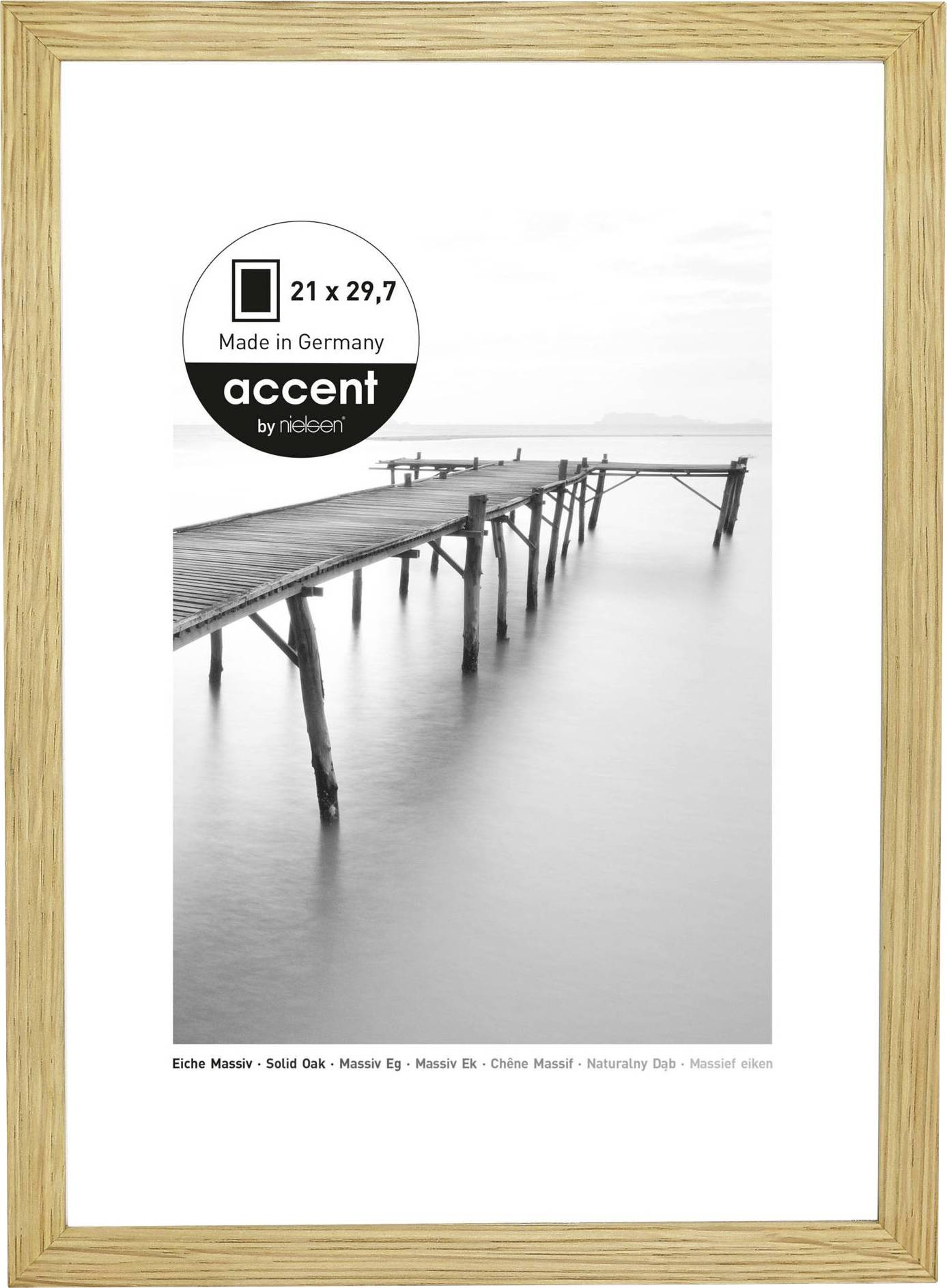 Drveni most se proteže u mirnu vodu. Desno gore naljepnica: '21 x 29,7, Made in Germany, accent by Nielsen'.