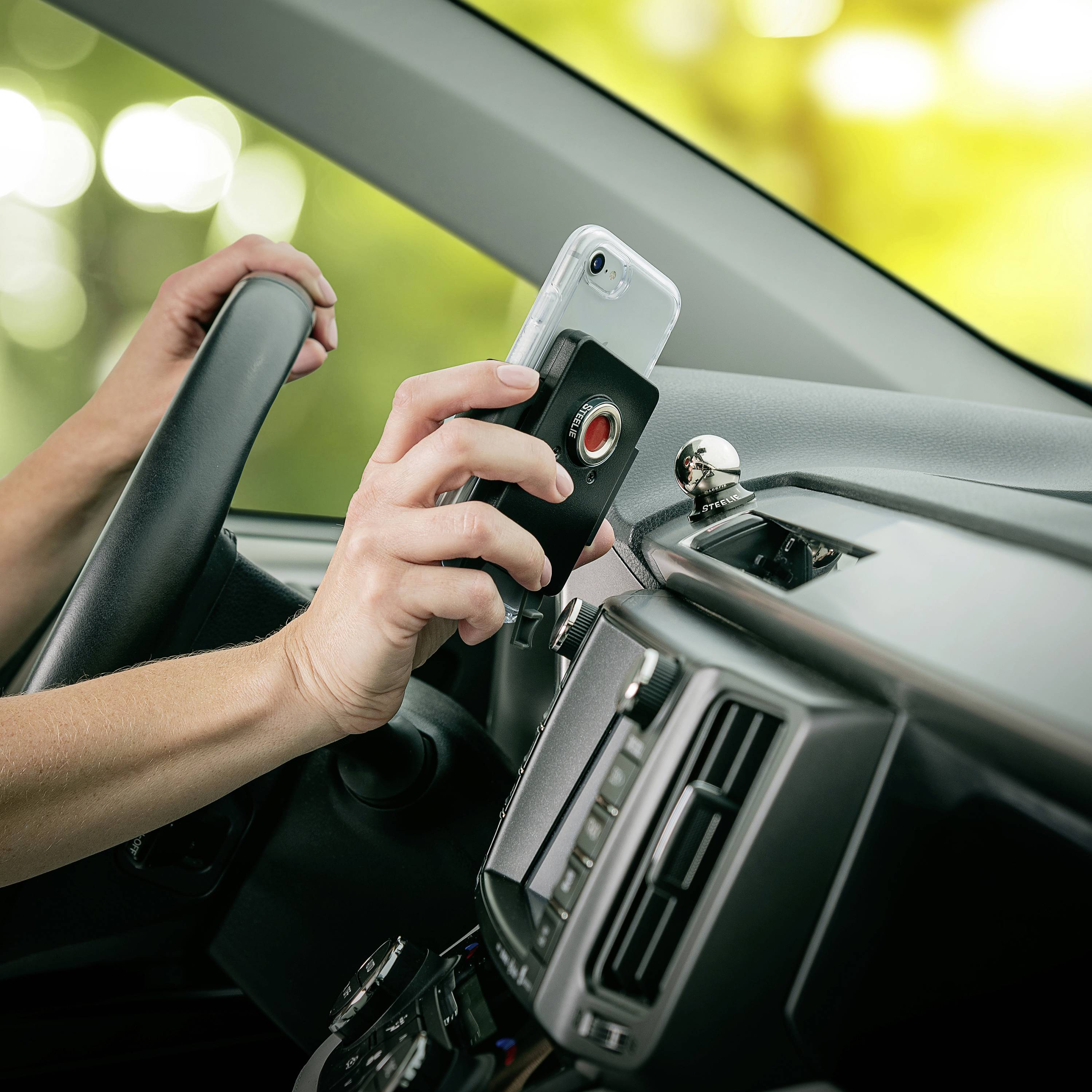 Osoba u automobilu učvršćuje pametni telefon na držač na armaturnoj ploči, vjerojatno za navigaciju.