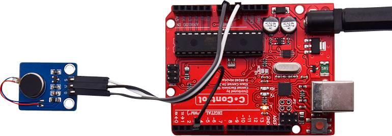 Crvena tiskana ploča Arduino mikroupravljača, spojena s manjim plavim senzorom. USB kabel spojen s desne strane.