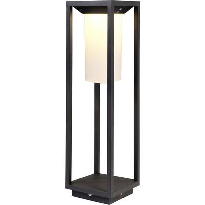 Moderna podna lampa s crnim, kubičnim okvirom i bijelim, cilindričnim sjenilom, nježno osvjetljavajuća.