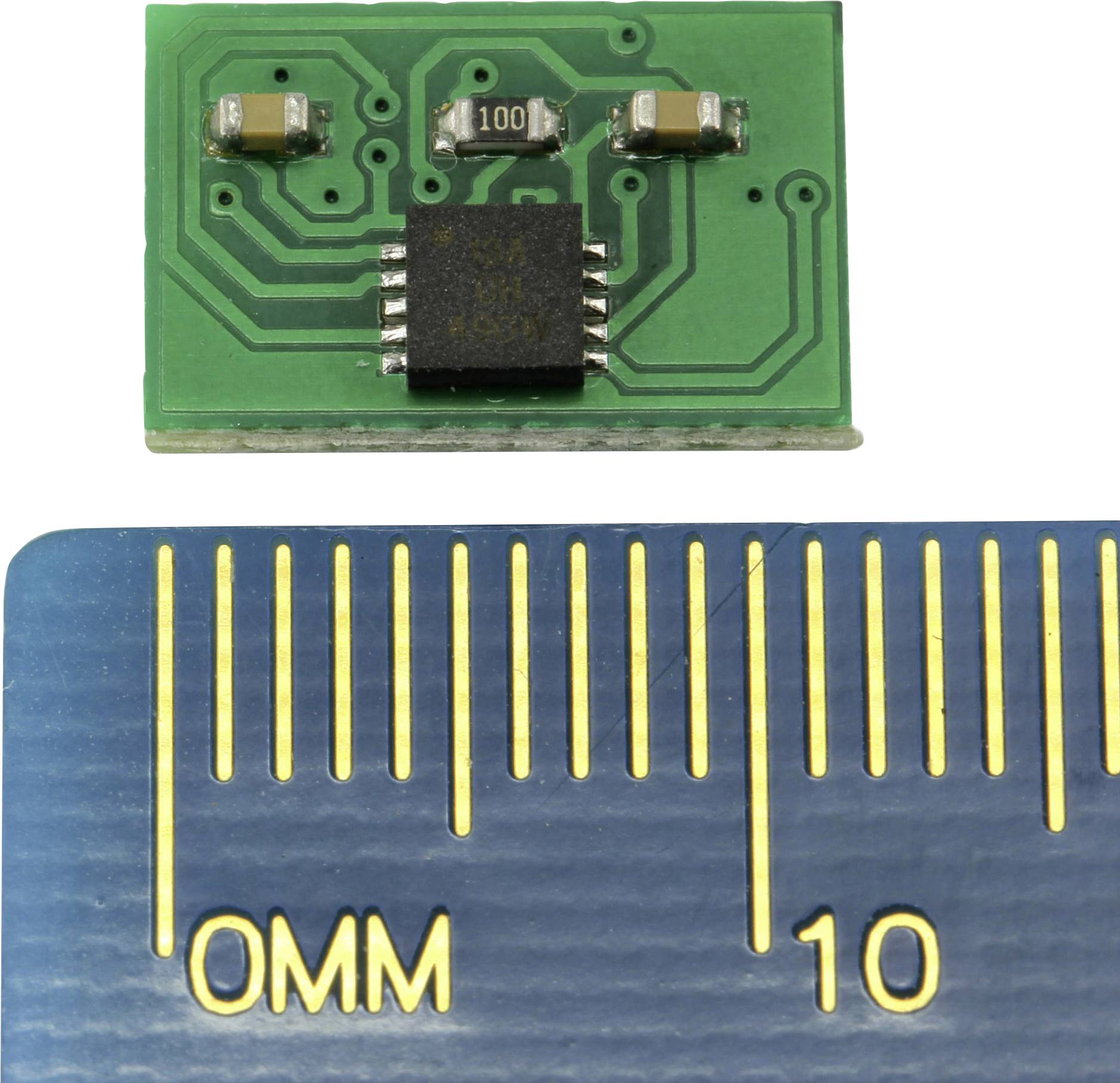 Bliski prikaz zelene tiskane pločice s integriranim strujnim krugom i malim komponentama, s ravnalom pored kao referencom veličine.