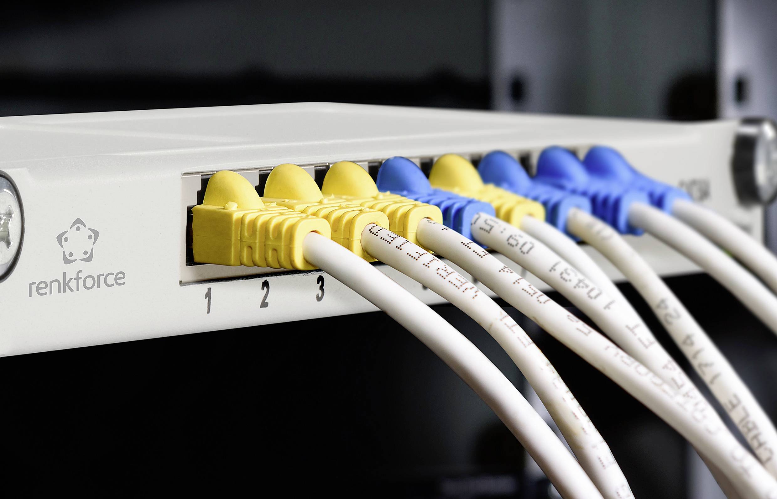Mrežni switch s više uključenih Ethernet kabela, žutih i plavih, pokazuje aktivnu povezanost nekoliko uređaja.