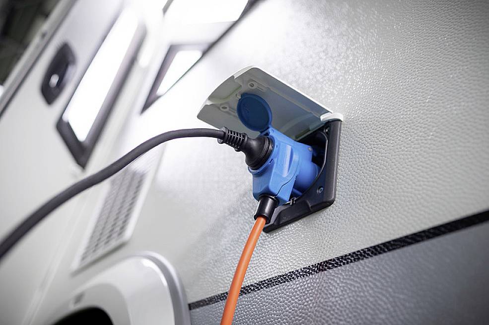 Narančasti električni kabel priključuje se na kamper kako bi mu osigurao napajanje strujom.