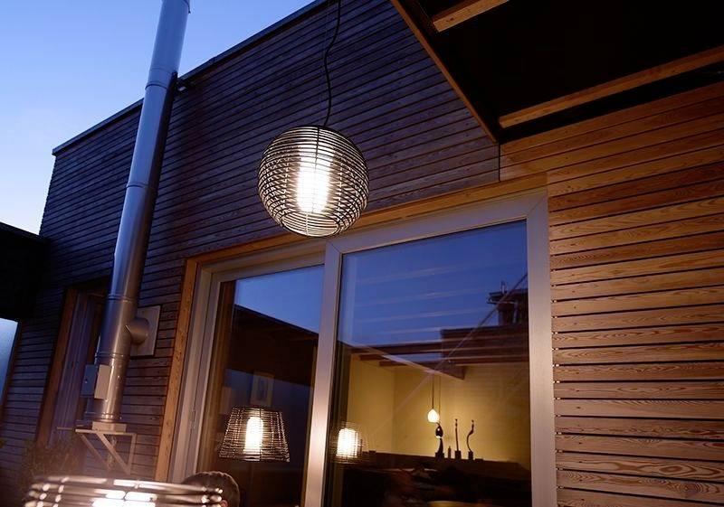 Suvremena terasa s drvenom oblogom i viseće lampe. Večernja atmosfera, osvjetljeni stakleni prozori reflektiraju prostorno svjetlo.