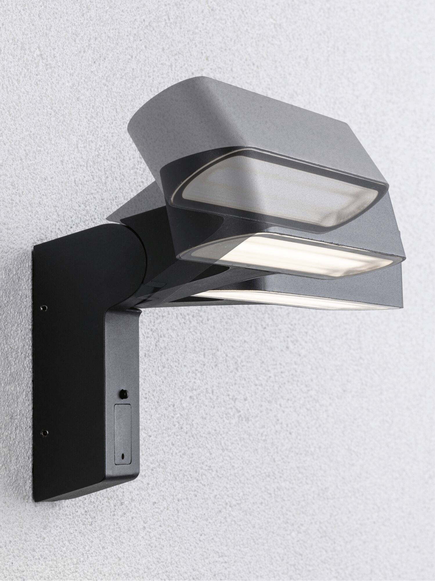Moderna vanjska zidna svjetiljka sa dvije pravokutne, okretljive lampe na crnoj konzoli, postavljene na bijelom zidu.
