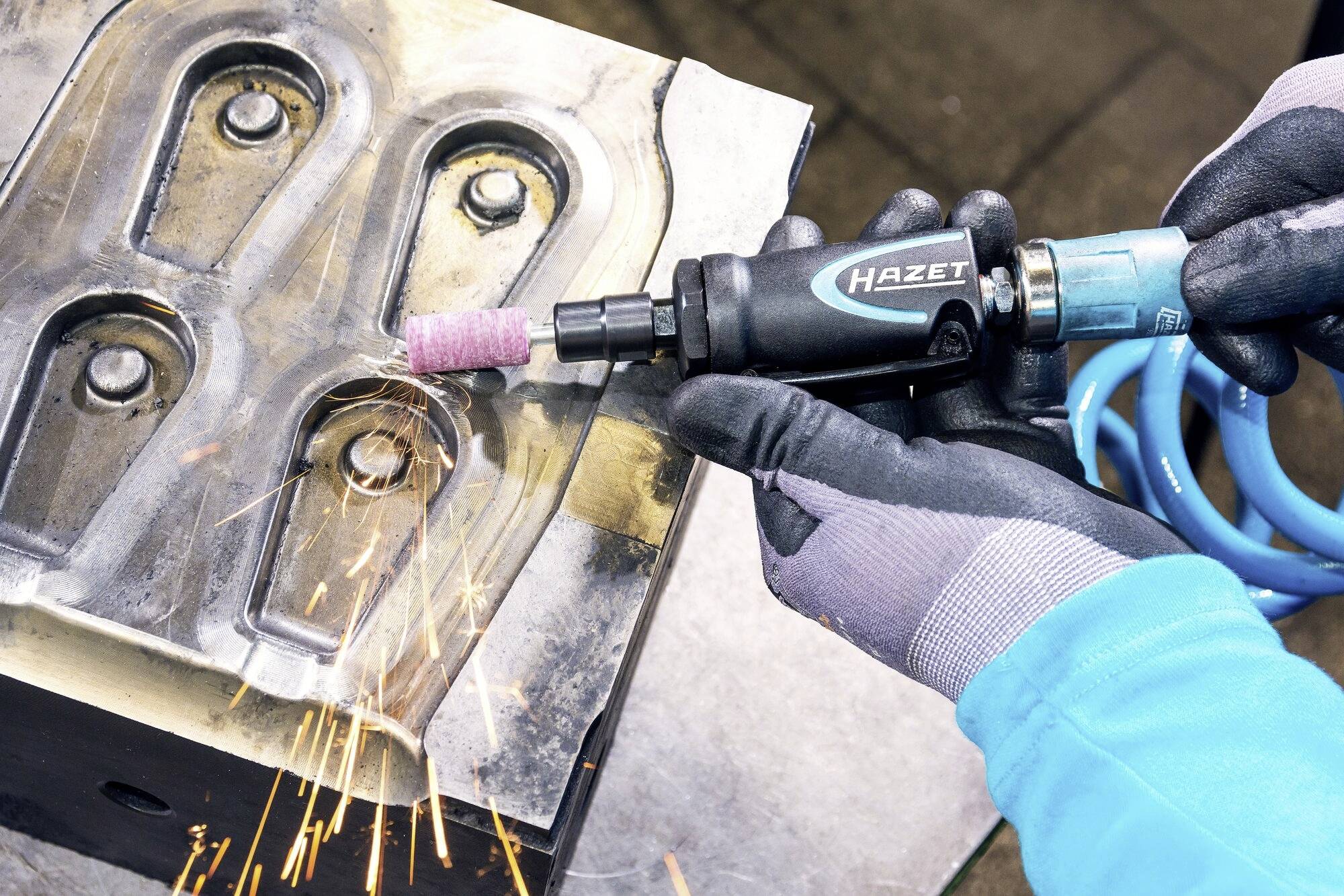 Osoba u rukavicama bruši metalnu površinu alatom marke 'Hazet', pritom šireći varnice.
