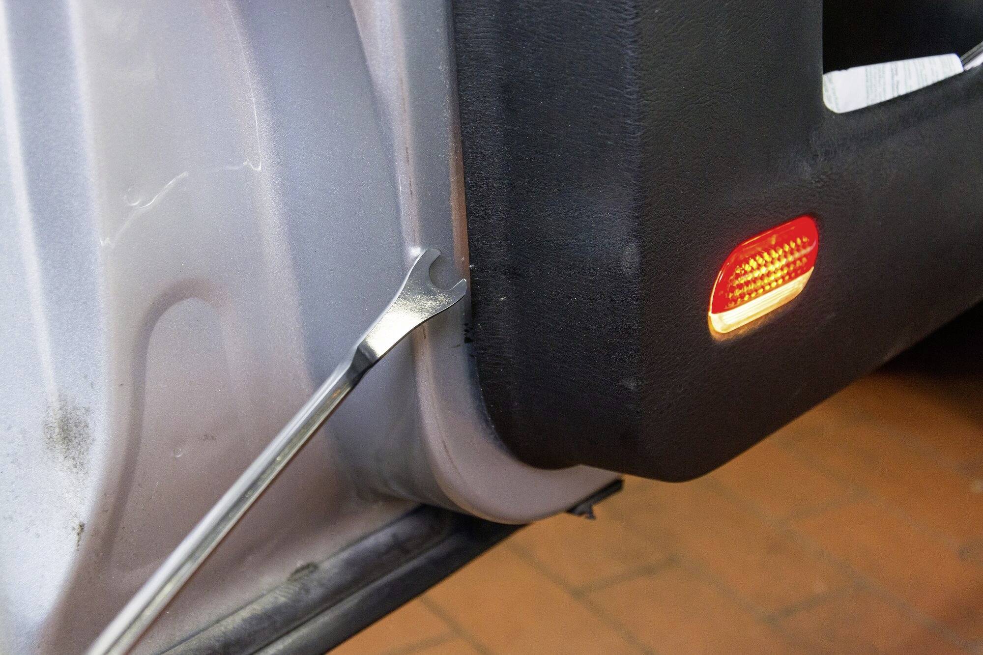Dizalica se koristi za uklanjanje obloge vrata automobila. Na oblozi se može vidjeti signalna lampica.