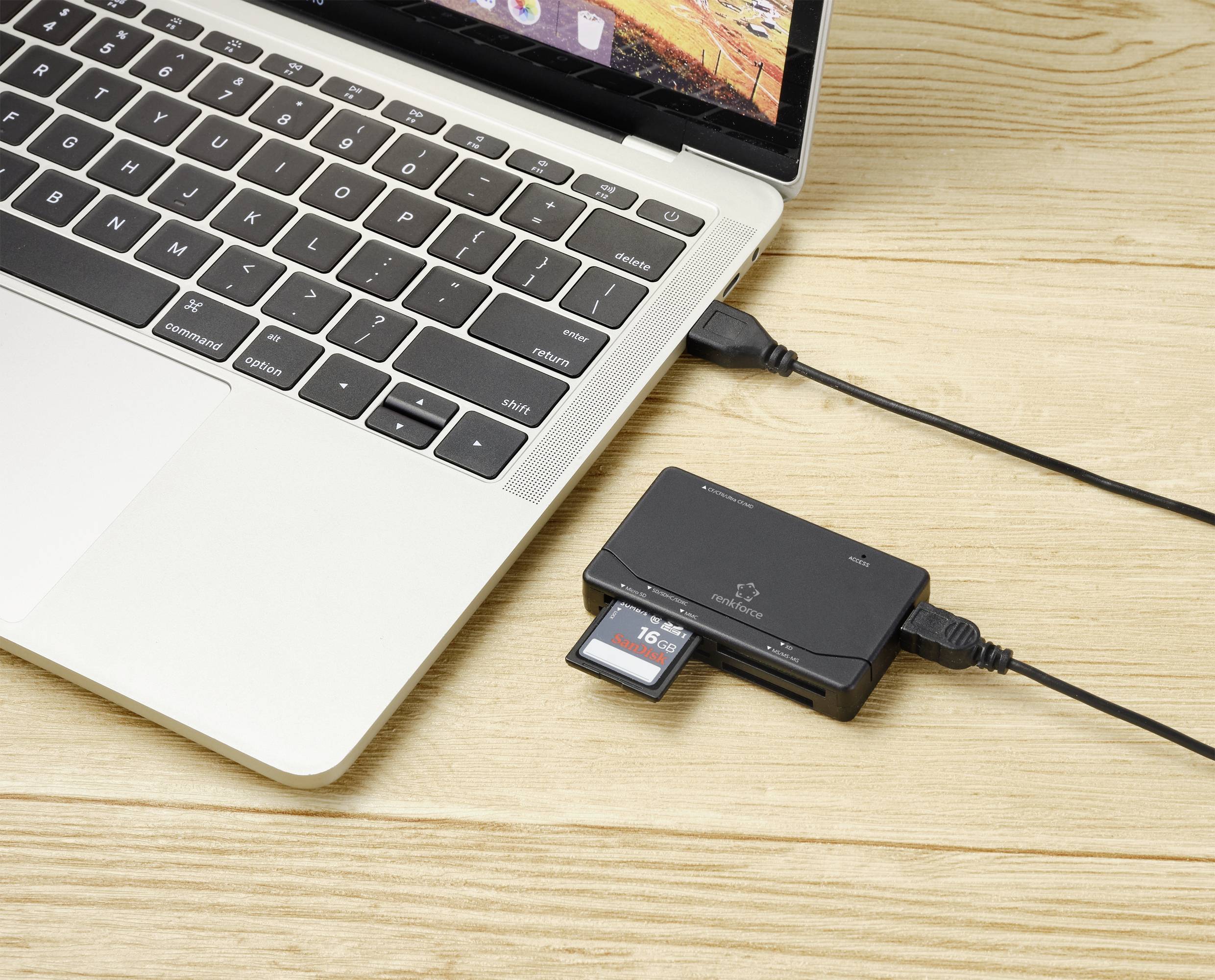 Prijenosno računalo na drvenom stolu spojeno je USB kabelom s čitačem kartica. SD kartica je umetnutna u čitač.