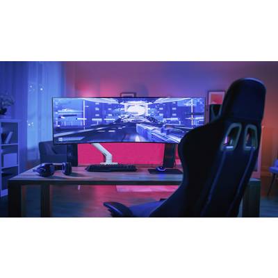 Računalni stol s velikim, zakrivljenim monitorom prikazuje videoigru. Ispred njega se nalazi gaming stolica u prostoriji osvjetljenoj crvenom i plavom bojom.