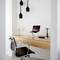 Minimalistički home office s drvenim pisaćim stolom, crnom stolicom, prijenosnim računalom na stalku i modernim lampama.