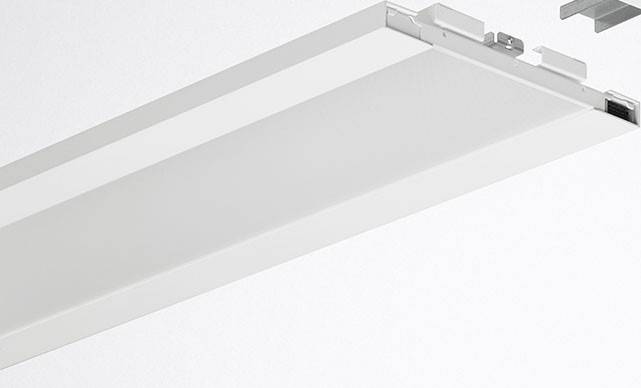 Bijela stropna lampa minimalistički dizajnirana, pravokutnog oblika, postavljena paralelno uz strop.