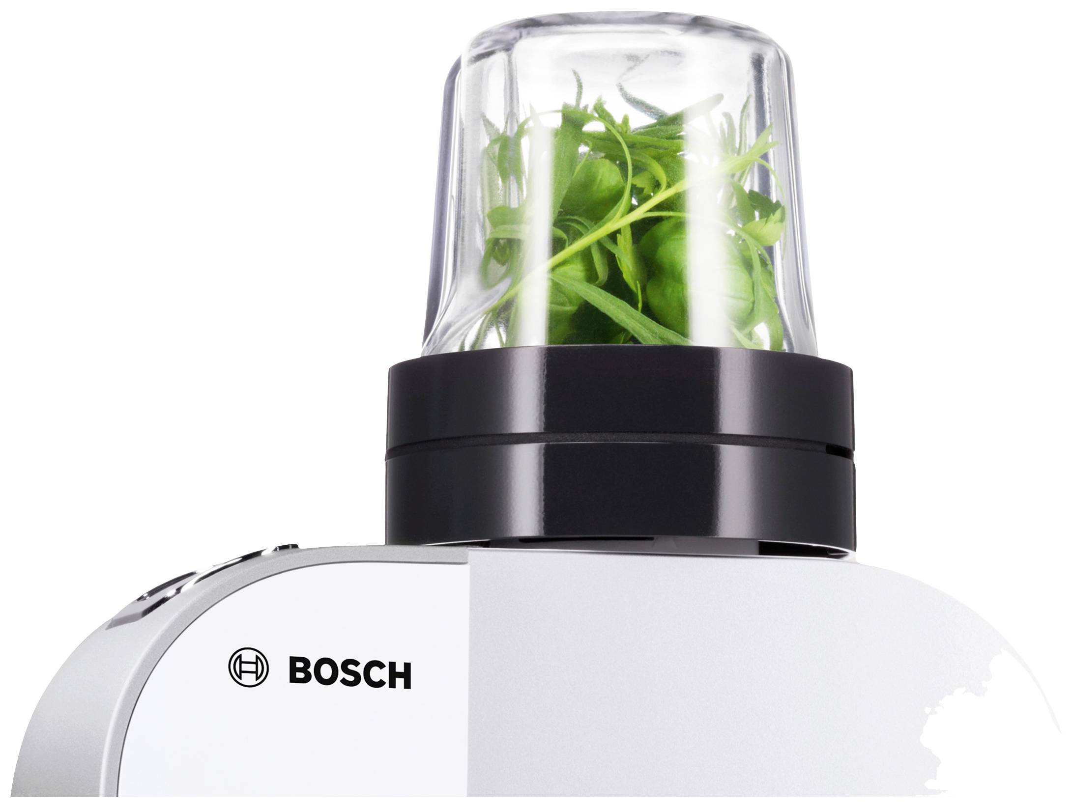 Kuhinjski uređaj s nastavkom, napunjen zelenim začinskim biljem. Logotip Bosch-a vidljiv je na uređaju.