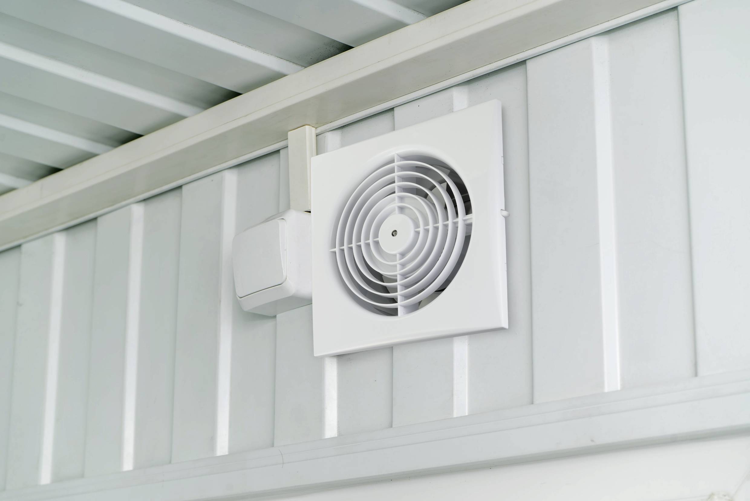 Ventilator za ventilaciju montiran na stropu za prozračivanje prostorija ili zgrada. Bijeli kvadratni poklopac oko ventilatora.