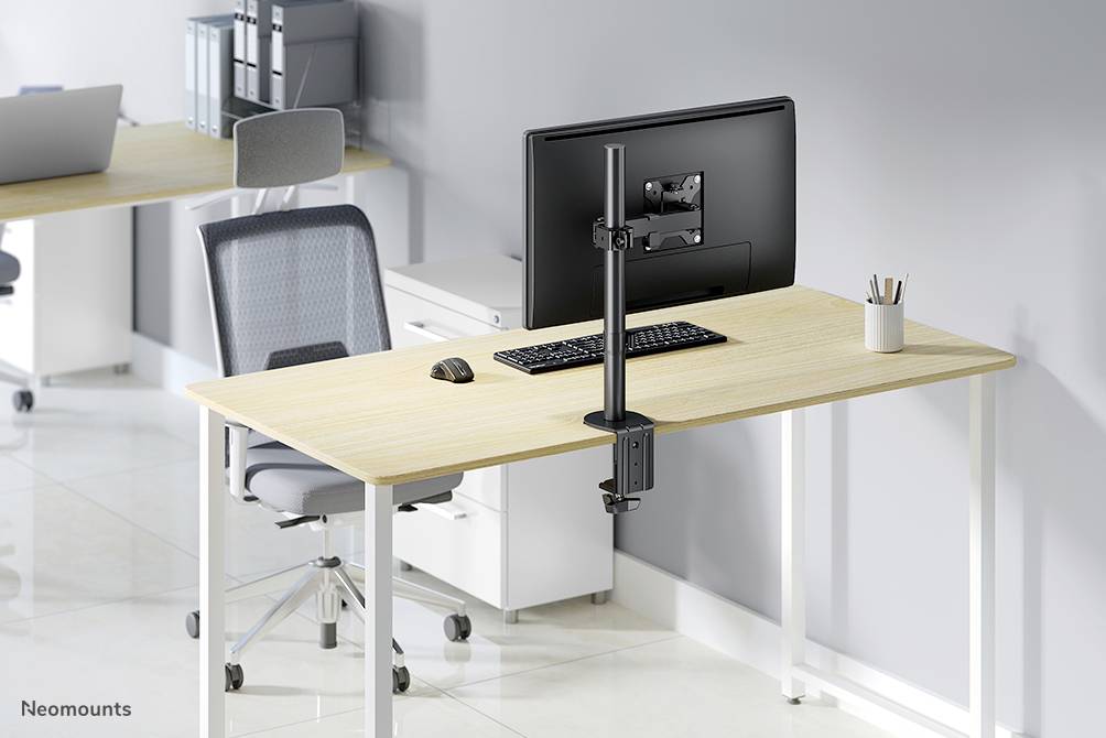 Moderan radni stol s monitorom, tipkovnicom i mišem, ergonomski uređen. U pozadini se vidi ostatak ureda s radnim stolom.