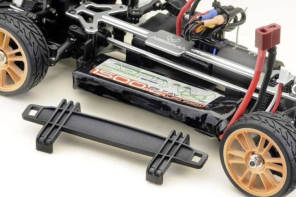 RC-auto šasija s vidljivom baterijom i elektronikom. Naranđaste kotače, kabelske spojeve i nosač ploču pored.