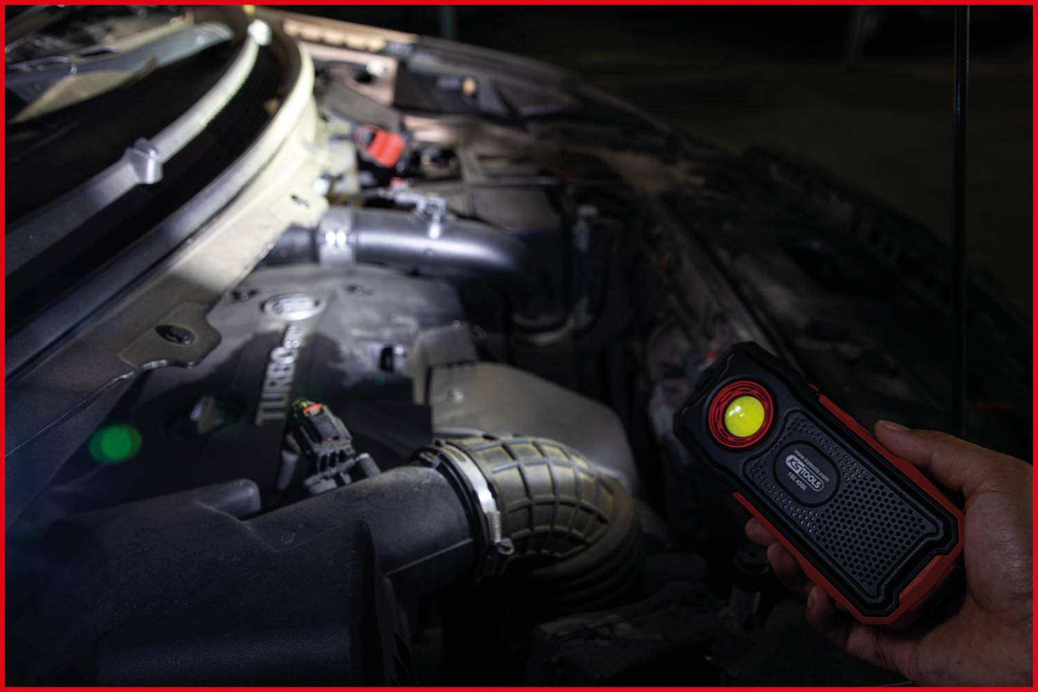 Jedna osoba osvjetljava motorni prostor prijenosnom lampom kako bi provjerila detalje motora.
