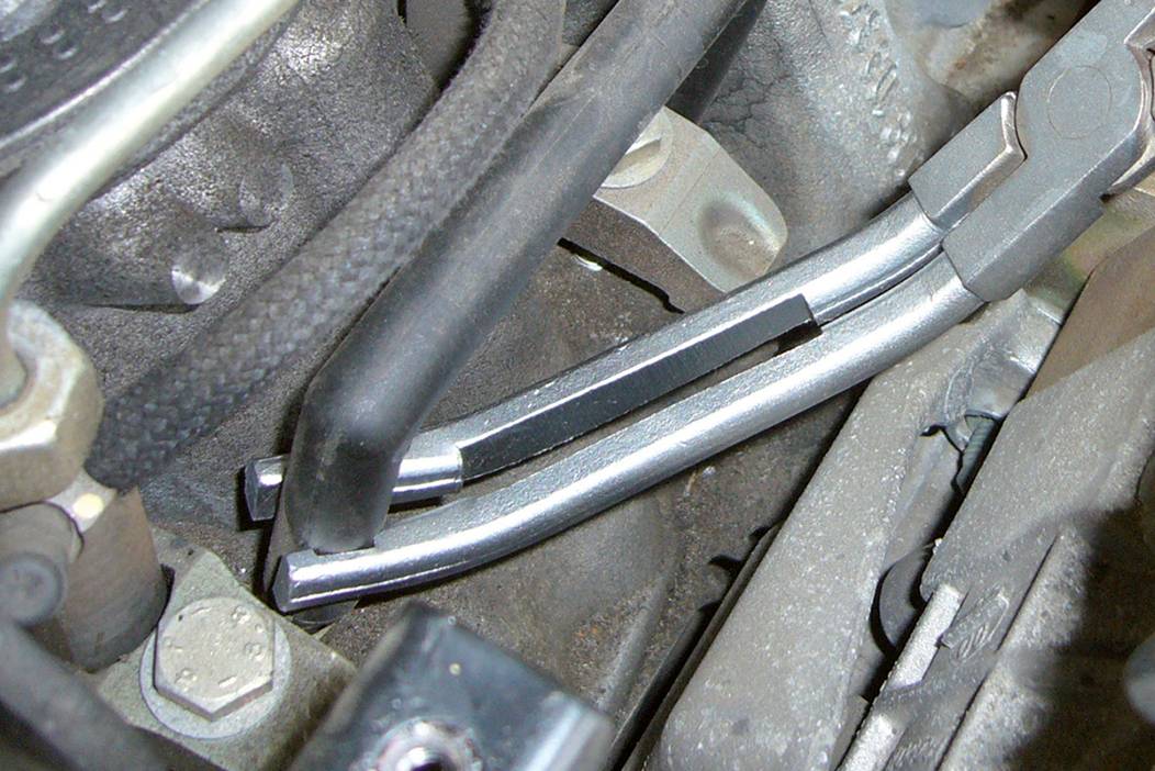 'Dva aluminijska cijevi povezana crnim cijevima u prostoru motora. Prikazuje tvorničko ožičenje u automobilu.'