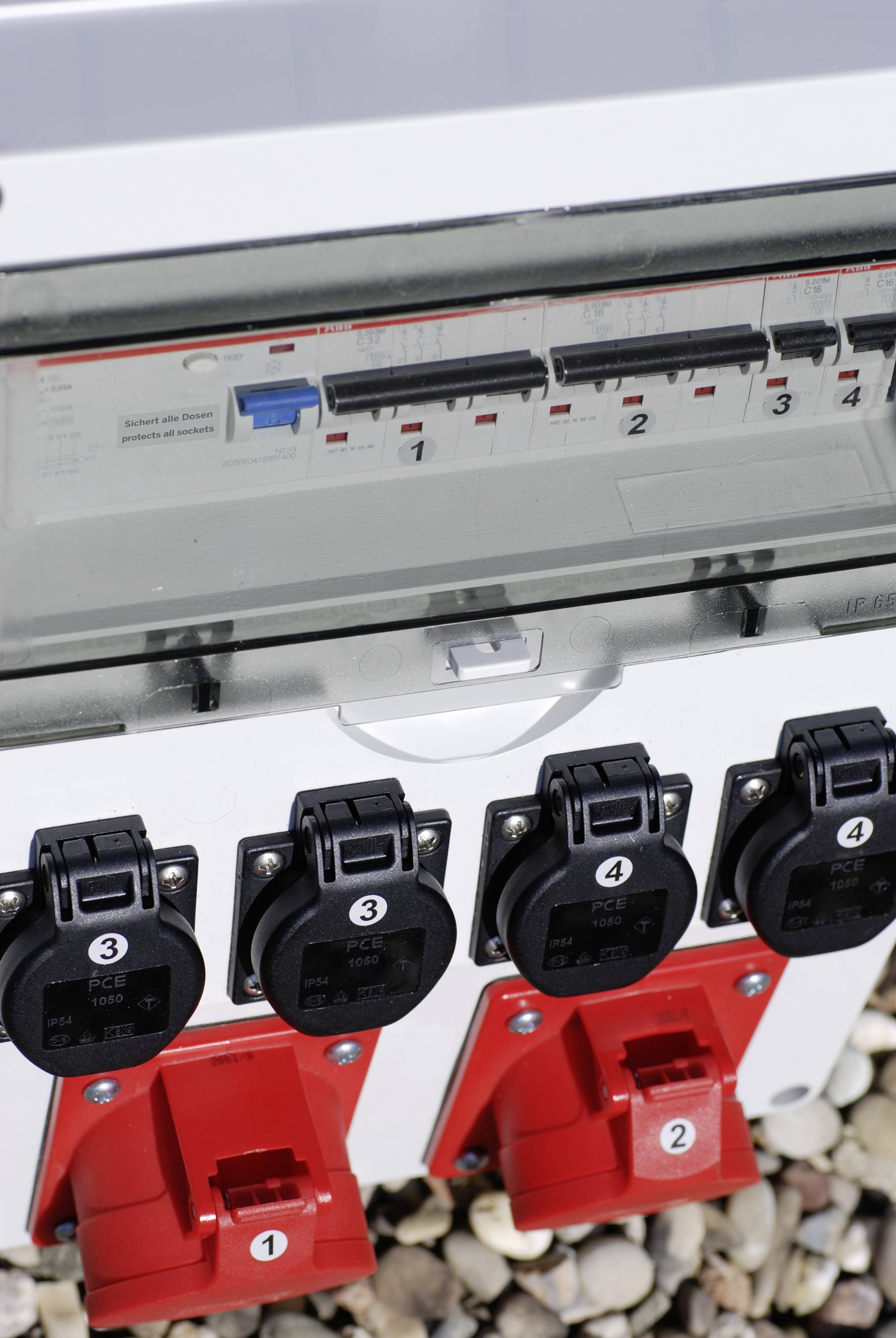 Električna razvodna ploča s četiri numerirane utičnice. Na vrhu se nalaze četiri numerirana prekidača u prozirnom kućištu.