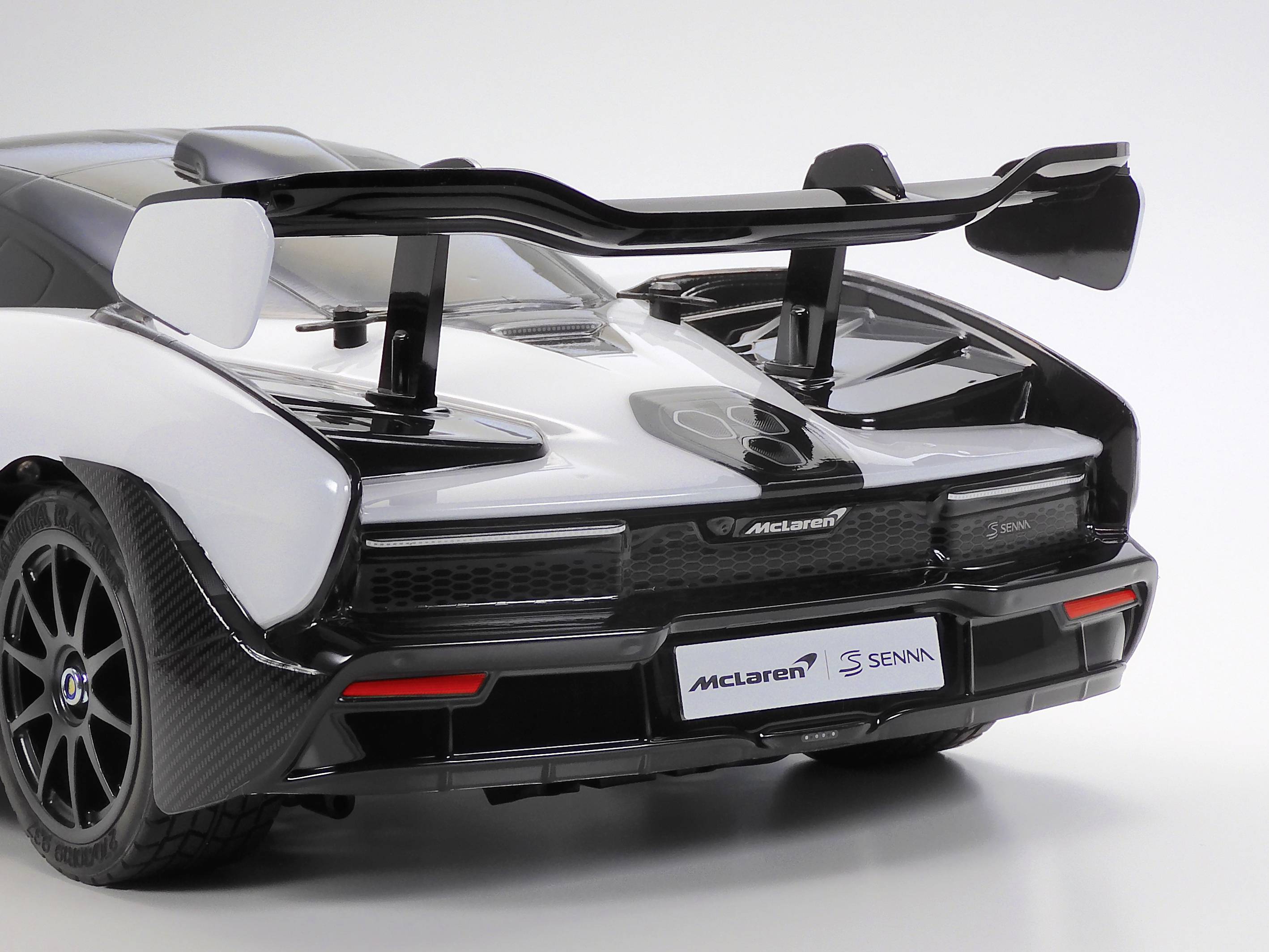 Sportski automobil s crnim stražnjim krilom na bijeloj pozadini. Na registarskoj tablici piše 'McLaren Senna'.