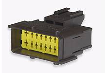 Crni električni konektor sa žutim kontaktima, korišten za električne spojeve.