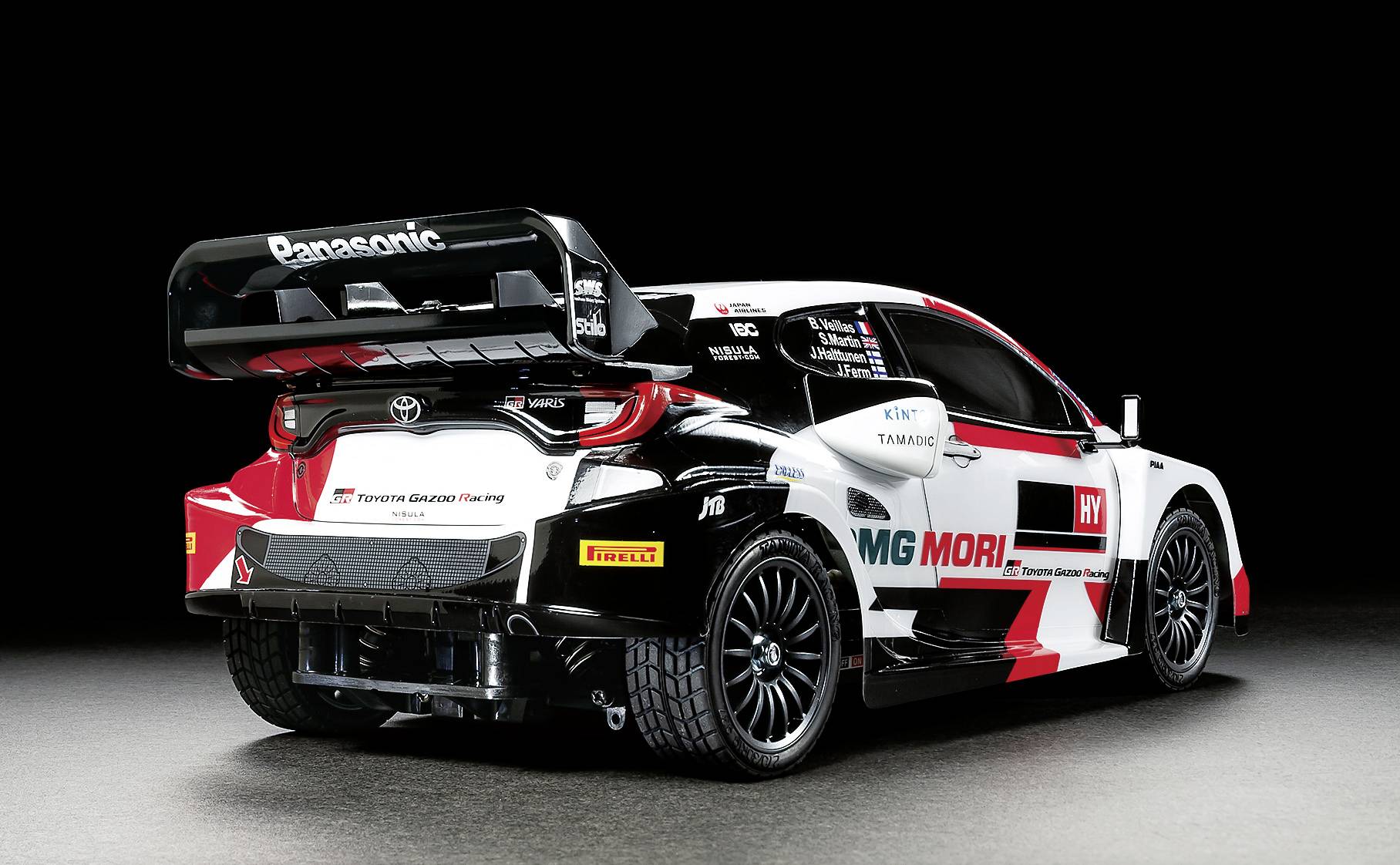 Rally-natjecateljski automobil s upadljivim logotipima i aerodinamičkim komponentama stoji ispred tamne pozadine, spreman za utrku.