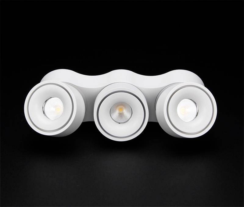 Tri okrugle, bijele LED lampice u valovitom nosaču, pred crnom pozadinom. Lampice su uključene.