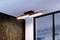 Moderna stropna lampa pravokutnog dizajna s LED svjetlosnim trakom visi u prostoriji pored prozora s roletama.