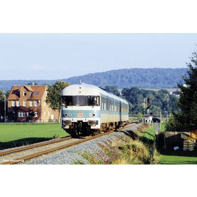 Vlak Deutsche Bahn vozi kroz ruralni krajobraz s kućom u pozadini i brdima na horizontu.