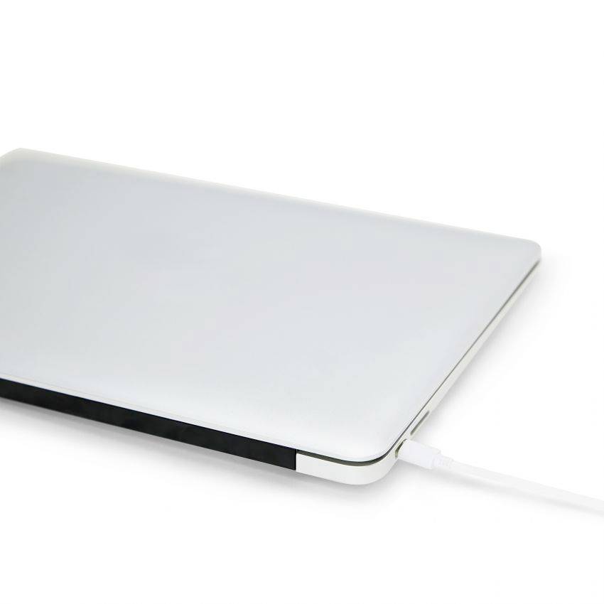 Zatvoreni srebrni laptop priključen na punjač na bijeloj pozadini.