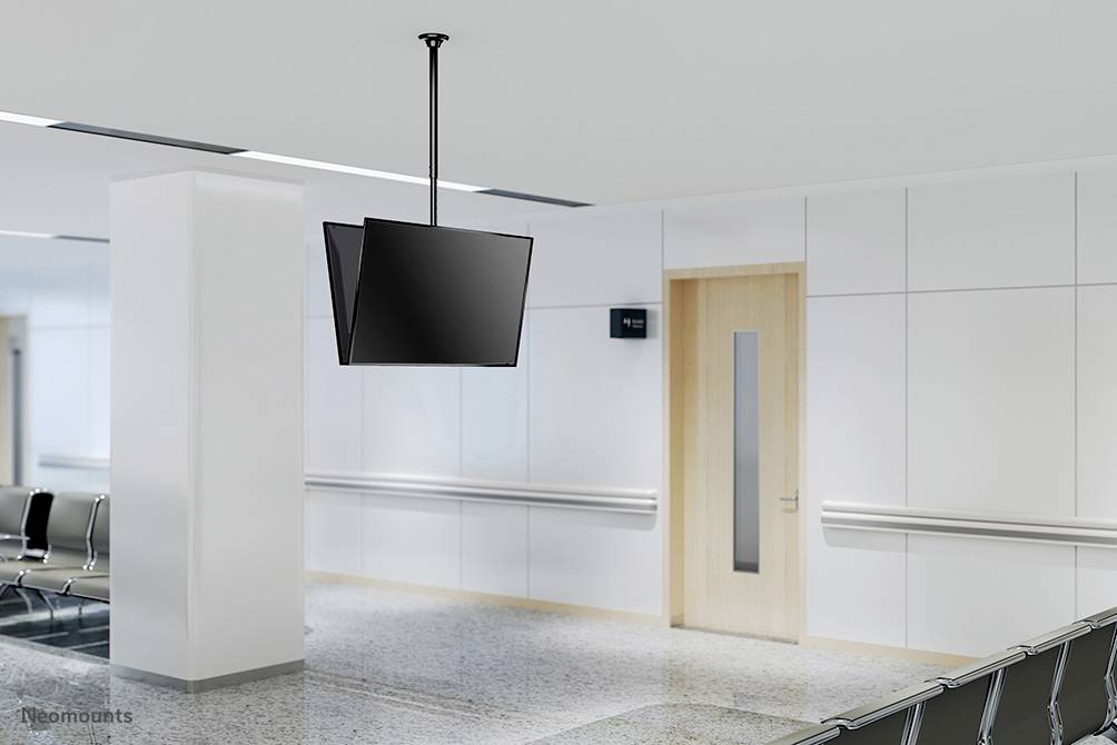 Prazan čekaonički prostor sa stolcima duž zida, viseći televizor i zatvorena drvena vrata.